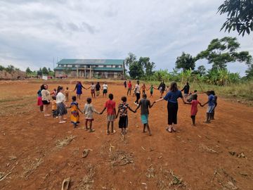 Viele Kinder stehen im Kreis vor dem Kinderheim und halten sich dabei an den Händen