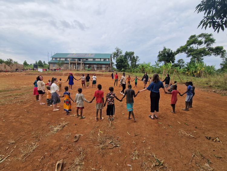 Viele Kinder stehen im Kreis vor dem Kinderheim und halten sich dabei an den Händen