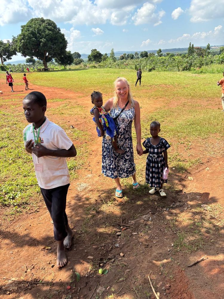 A woman is carrying a child and is holding a child's hand