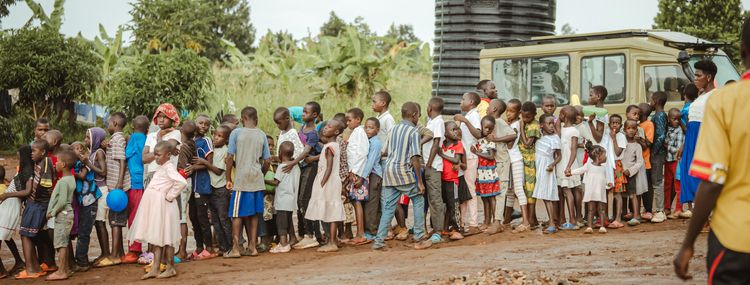 Kindern stehen in einer Schlange vor einem Brunnen in Uganda