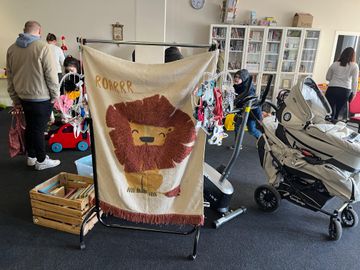Ein Wandbehang, ein Kinderwagen sowie Spielzeug werden zum Verkauf angeboten